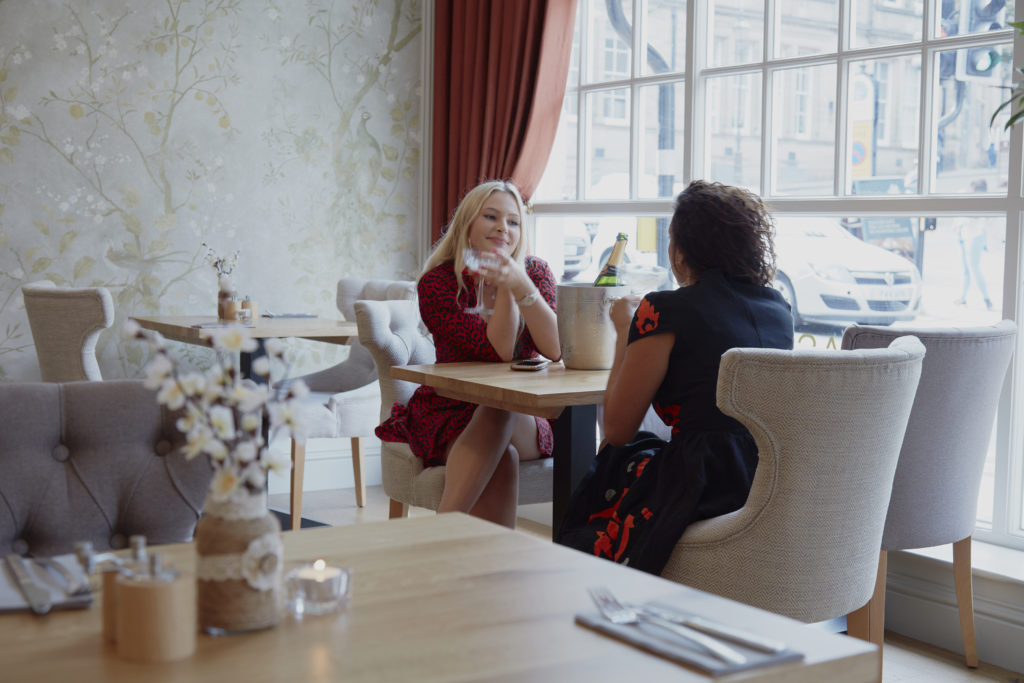 Two females sat drinking champagne